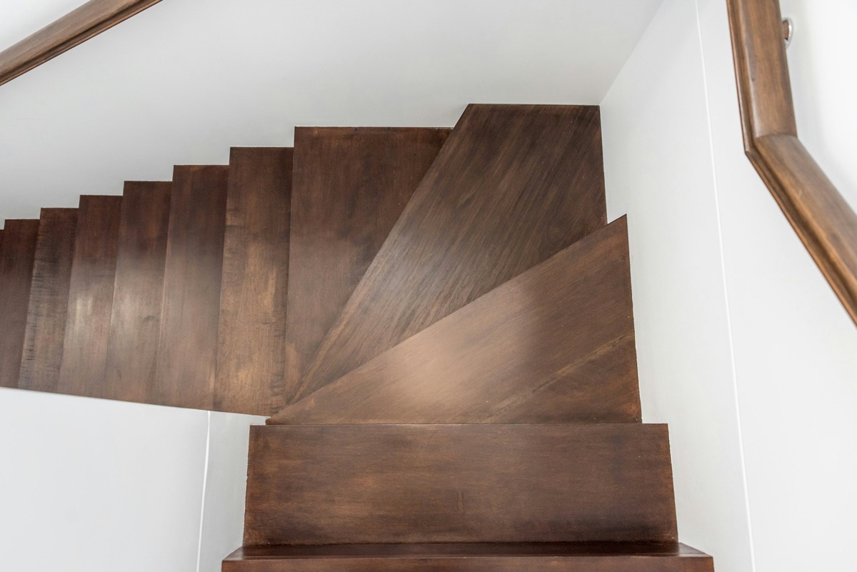 Escalier quart tournant en bois foncé entre deux murs blancs